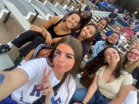 Group of students sitting in a sports stadium, posing for camera.