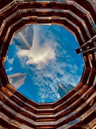 Tops of skyscrapers pictures through an opening at the top of a building.