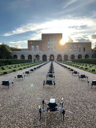 Fondren library in the background, with drones in structured lines and rows on the ground in front of the building.