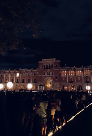 Lovett Hall in the dark. Several people gathered in the foreground.