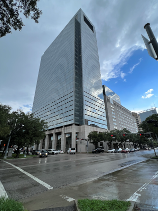 City street crossing with a tall building in the opposite corner. Photo taken from a low angle.