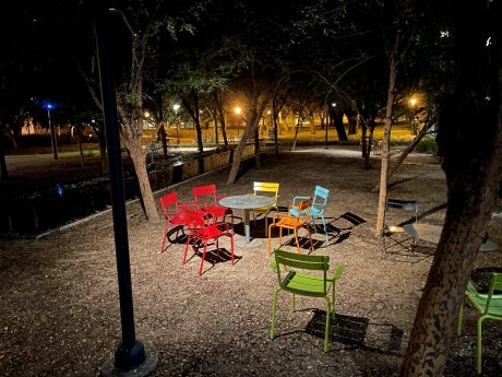 Colorful chairs grouped around a table in an empty courtyard at night.