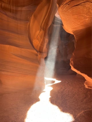 Narrow pathway of a canyon. Sunlight filters in from the top of the image.