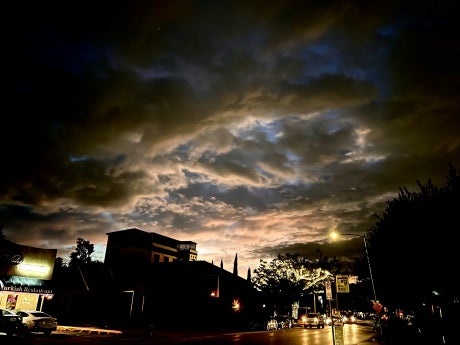 View of a city street at night with dark clouds on the sky.